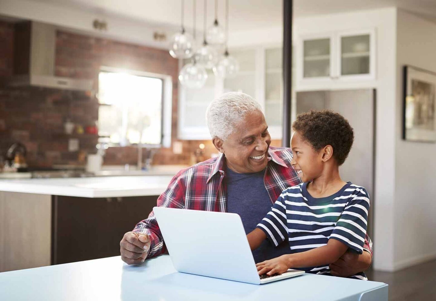 A grandfather sitting at a desk with his grandson sitting on his lap