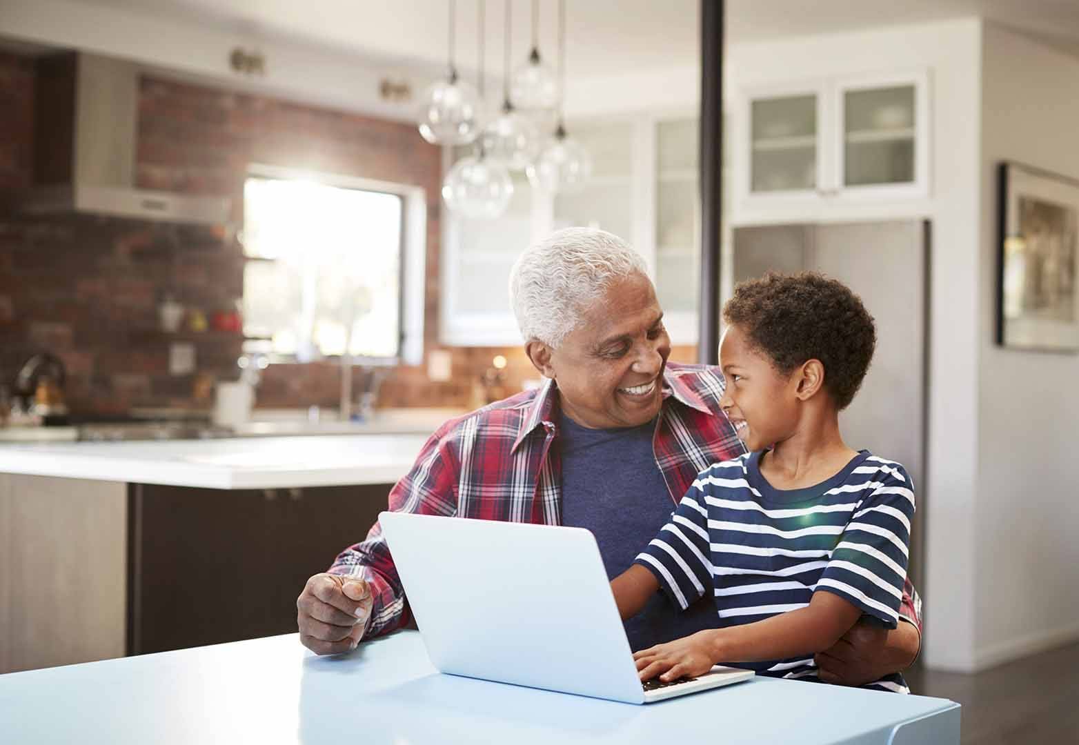 A grandfather sitting at a desk with his grandson sitting on his lap