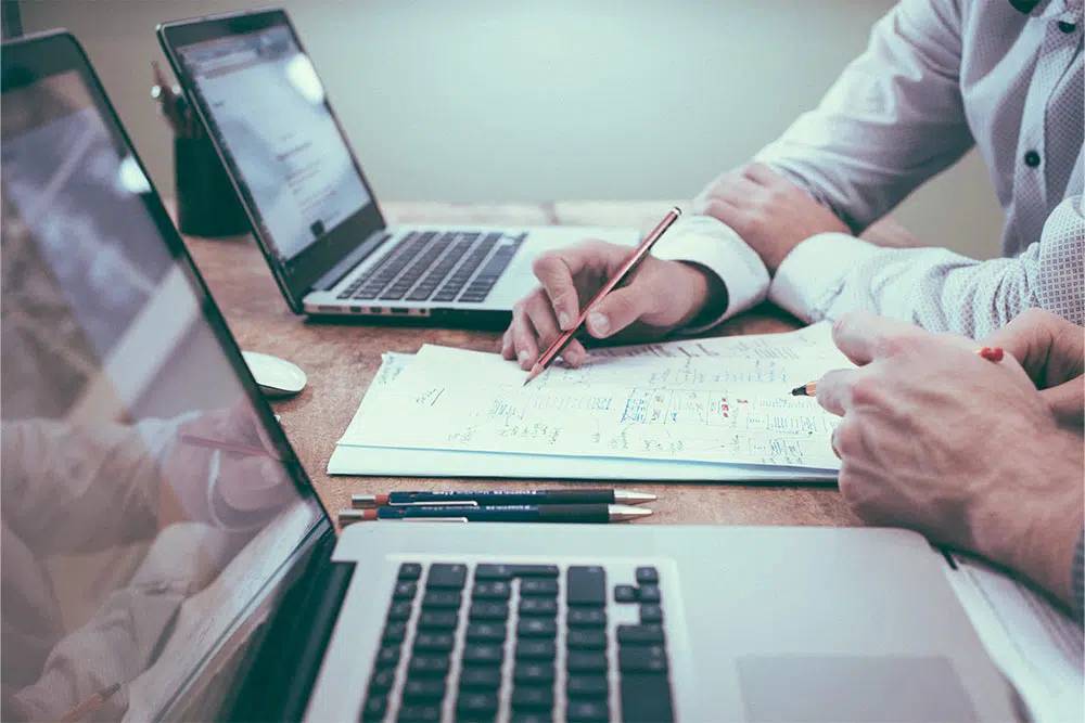 Two people sitting at a desk collaborating on some paperwork