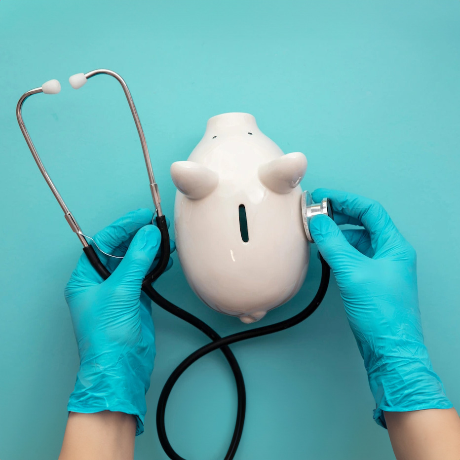 A pair of hands holding a stethoscope to a piggy bank