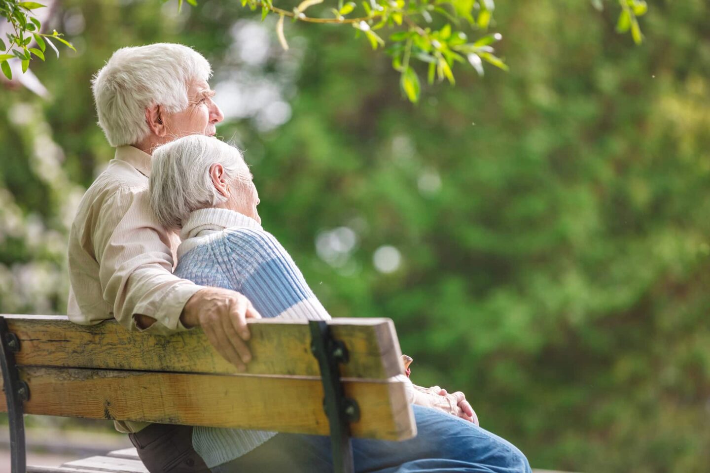 An elderly couple sitting on a park bench