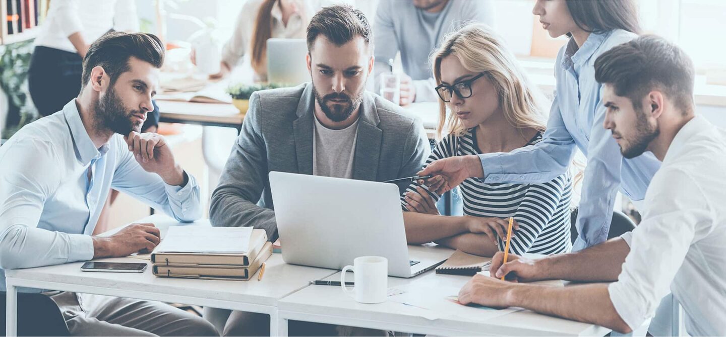 A group of insurance brokers sitting around a table working on a laptop
