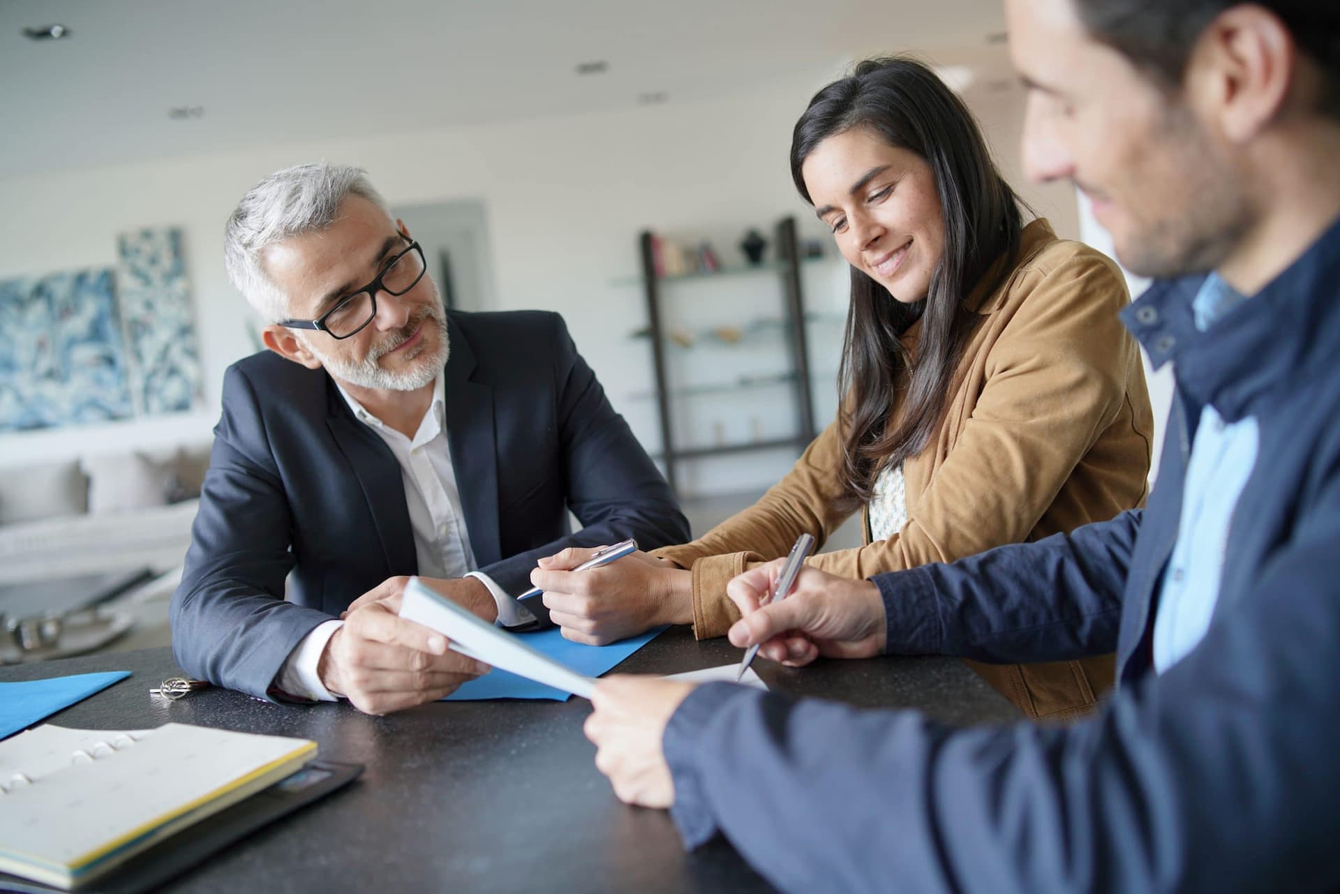 A young couple signing documents that an agent is holding