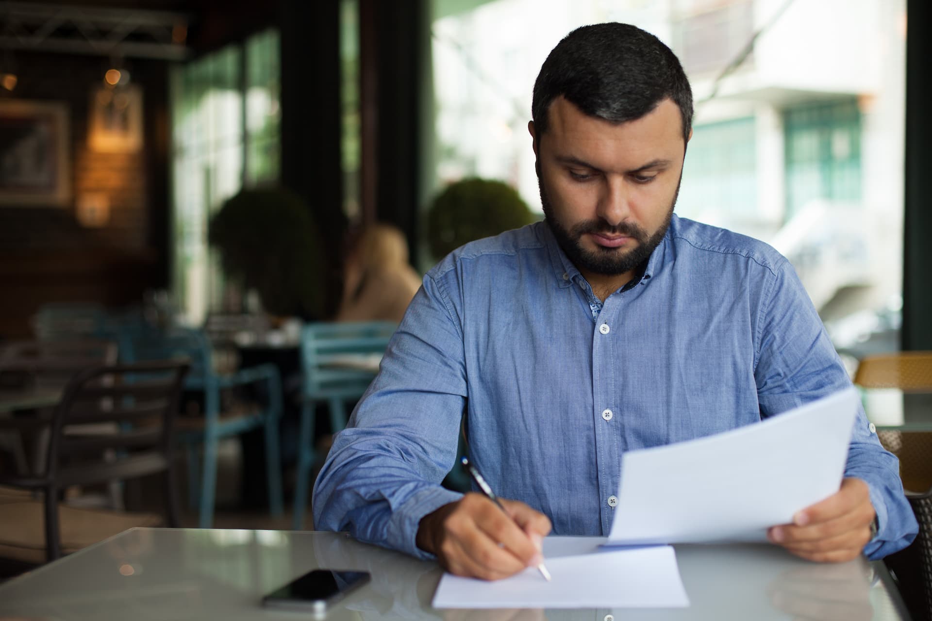 A man sitting in a cafe writing his resume
