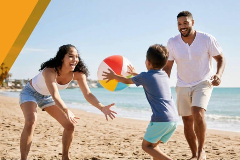 Family playing with beach ball on sunny beach in Canada.