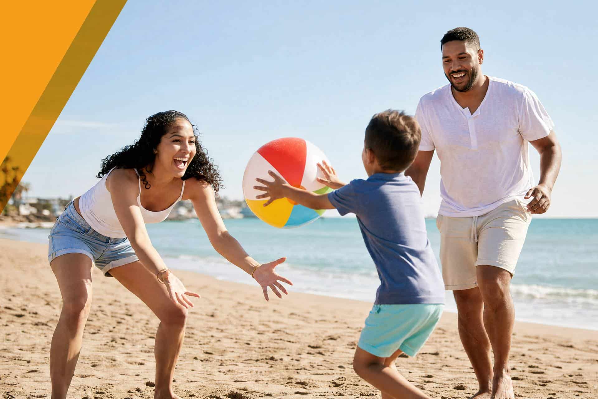Family playing with beach ball on sunny beach in Canada.