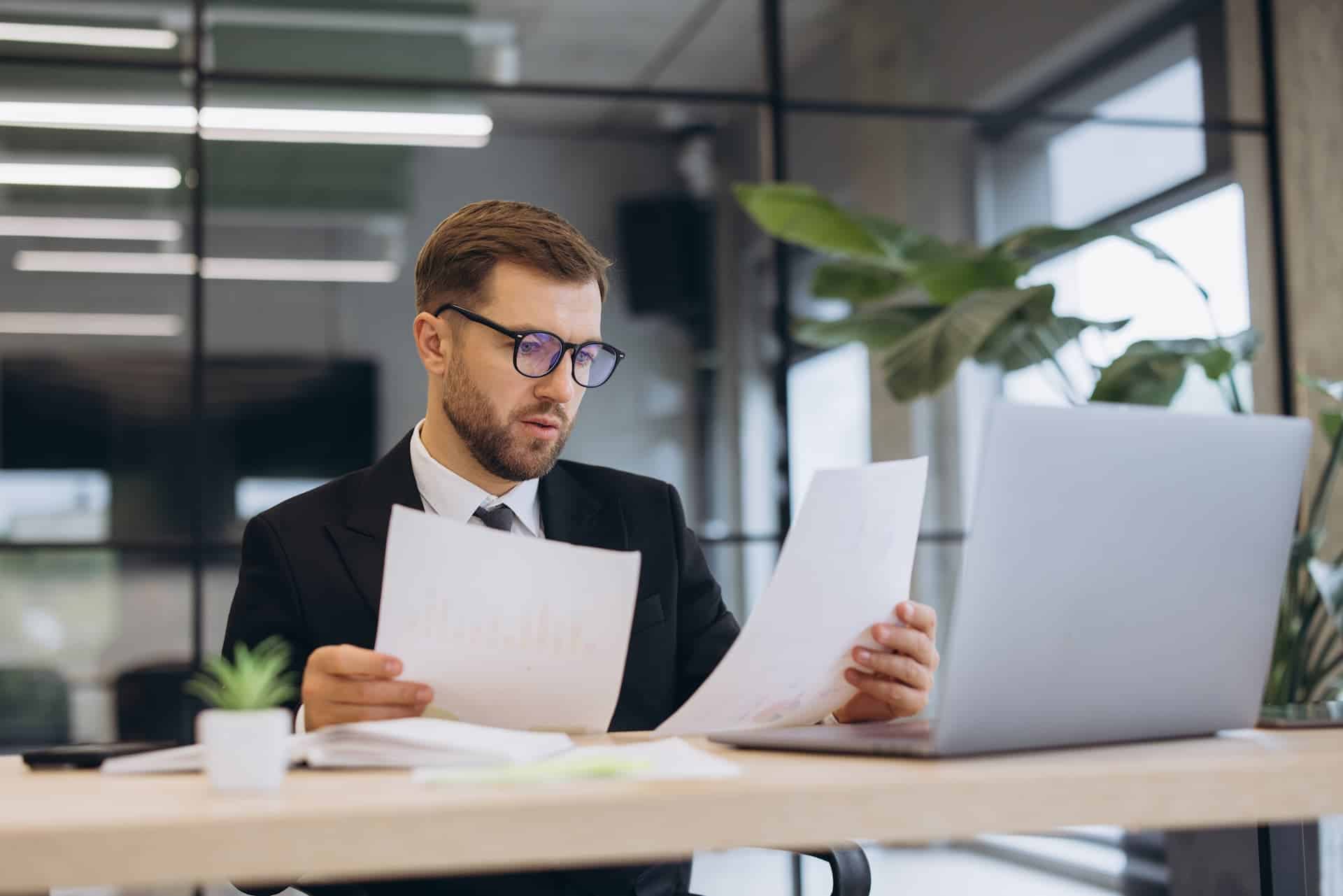 Insurance broker reviewing carrier product data and reports at his desk
