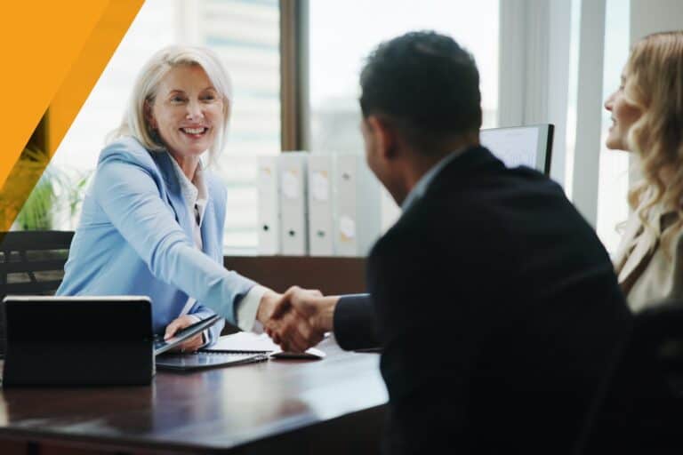 Financial advisor shaking hands with clients in a professional setting.